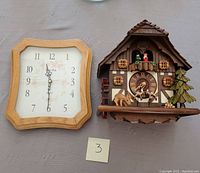 Two clocks shown side by side: Bulova wall clock on left and German cuckoo clock on right