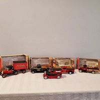 Five diecast antique truck coin banks displayed on table with four original boxes in background.