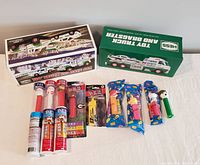Lot overview showing Hess Toy Truck in box and multiple Pez candy dispensers, some in tubes and others in packaging.