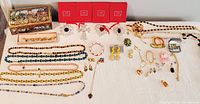 Full lot overview showing jewelry spread with Lenox red ornament boxes and decorative tin box at left