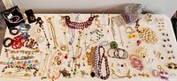 Overhead view of entire jewelry assortment spread on table, showing mix of necklaces, bracelets, earrings, brooches and loose beads