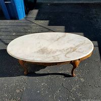 Full view of the oval marble top coffee table showing overall shape and condition.
