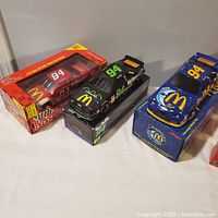 Three McDonald's branded diecast NASCAR collectible cars. One red #94 car in original box, one black #94 car on box, one blue #94 car on box.