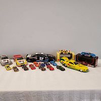 Overview photo showing full collection of 18 NASCAR diecast cars of varying sizes and designs, two in display boxes.
