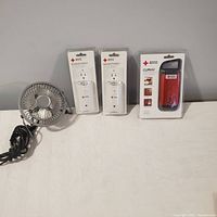 Lot overview showing two Blackout Buddy flashlights in packaging, new unopened Clipray red flashlight packaging, and mini metal fan with cord.