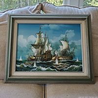 Full view of framed oil painting showing two ships in combat at sea, with silver-gray frame and white matting.