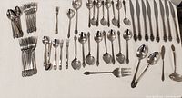 Full set spread out on white cloth showing knives, forks, spoons and specialty pieces arranged neatly