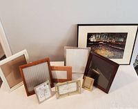 Photo showing multiple empty picture frames and two large Boston Celtics wall art pieces with basketball court and banners, arranged on a surface.