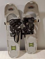 Pair of white Bearpaw Hike snowshoes with green HIKE stickers, black adjustable bindings, visible metal rivets, side by side facing forward.