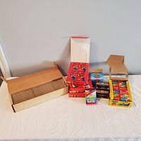 Wide front view showing a box filled with loose baseball cards, stacks of unopened baseball card packs including the 1985 Topps set, and other unopened boxes of baseball cards.