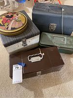 Five assorted storage lock boxes of various materials and sizes, assorted colors, stacked on floor.