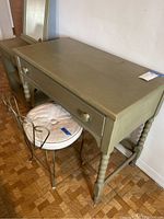 Wooden vanity table with single drawer and turned legs, paired with metal vanity chair with cushion