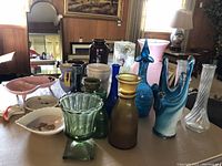 Wide shot showing various vases and bowls in different colors and materials arranged on a table