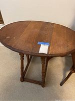 Full view of the vintage wooden drop-leaf side table showing the overall shape, turned legs, and drop-leaf extended on one side.