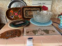 Overview of glass bowls, trays, and other items on pink tiled surface.