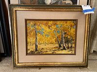 Framed fall trees canvas painting with yellow foliage, gold highlights, and blue sky accents. Brown-gold frame with beige mat. Size approximately 21x17.5 inches.