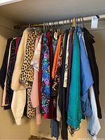 Photo showing a rack of assorted women's jackets, blouses, and pants in medium to extra large sizes with varied patterns and colors including leopard print, floral, blue, black, and orange.