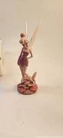 Front view of Tinker Bell figurine showing standing pose, pink sparkly dress, and floral base.