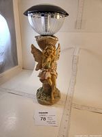 Full view of 14" fairy solar light with solar globe on top and fairy figurine base, with measuring tape showing 14 inches in height.