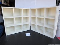 Two white wooden 9-cube storage shelves side by side visible front