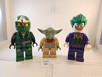 Front view of all three LEGO character clocks showing digital time on torso: Ninjago Lloyd, Star Wars Yoda, and Batman Joker