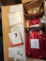 Porcelain doll in original packaging with Certificate of Authenticity and informational booklet visible.