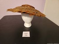 Side view of feather derby hat on mannequin head, showing wide floppy brim with natural feather edges.