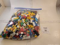 Clear plastic zip bag filled with loose assorted multicolored plastic building blocks in LEGO style, displaying size and quantity.