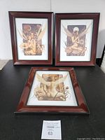Three David Delamare fairy prints in brown wooden frames with decorative bead detailing, arranged with two vertical and one horizontal print, displayed on black table