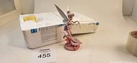 View of the Tinker Bell figurine standing on a pink flower base with Styrofoam original packaging in the background.