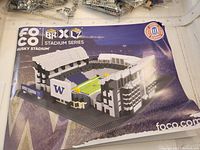 Photo of the Husky Stadium building kit box and instruction manual showing stadium model image