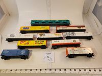 Ten HO scale railroad cars displayed in a row with ruler for scale, showing various colorful boxcars and livestock cars with advertising and brand logos.