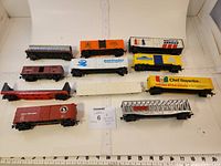 Lot of 11 HO scale model train cars arranged in rows with ruler for scale, showing various colors and company decals
