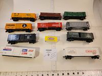 Top-down group view showing all 10 railroad cars and 1 small yellow container on a white surface with ruler for scale.