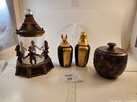 Full view of all four items in the lot on white backdrop with measuring ruler: two Egyptian canopic jar replicas, monkey glass jar with lid, mosaic bowl with lid