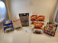 Seven Hot Wheels and Route 66 die-cast cars in original packaging displayed together, showing different models and packaging styles.