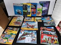 Photo of wide lot of Lego instruction manuals and books arranged upright and flat on a surface showing multiple Lego series including Mindstorms, City, Star Wars, Creator, Juniors.