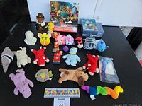Full view of the lot on black table showing puzzles, plush toys, and watch.