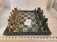 Full view of vintage handmade Crusaders chess set on decorative board with ruler indicating board width of about 15.5 inches.