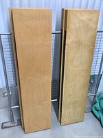 Four wooden floating shelves stacked vertically against a metal frame, showing their length and width with natural wood grain and minor surface wear.