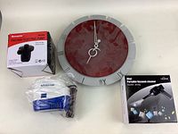 Photo showing the round wall clock with maroon face, two-way electric pump in box and unpacked, and boxed mini portable vacuum cleaner.
