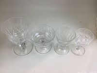 Close-up of four crystal glasses showing different styles and intricate cut designs on the bowls and stems.