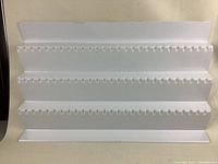 Front view showing the white plastic spice holder with multiple notches arranged in four angled rows designed to hold spice bottles.