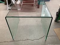 Front view of the modern clear tempered glass waterfall end table with smooth curved edges and transparent surface.