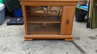 Front view of wooden cabinet showing glass sliding doors and solid side panel door with metal handle.