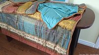 Duvet cover laid flat showing multicolored patchwork design with a teal backing and orange trim