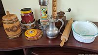 Overview of assorted vintage kitchenware including tins, wooden items, metal pitcher, rolling pin, and Corning Ware casserole dish