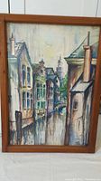 Frontal image of watercolor painting showing houses along a canal in pastel colors with rustic wood frame
