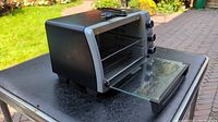 Black and Decker toaster oven with door open showing interior wire rack and crumb tray.