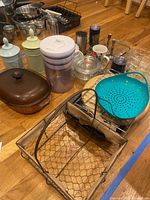 Full lot showing large brown metal cake pan, decorative canisters in pastel colors, plastic canister, wire basket, and metal baking racks.
